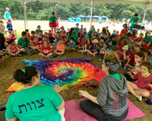 Campers sitting in a circle at Jewish summer camp outdoors