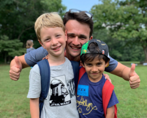 Two young campers and camp counselor smiling outside in grass